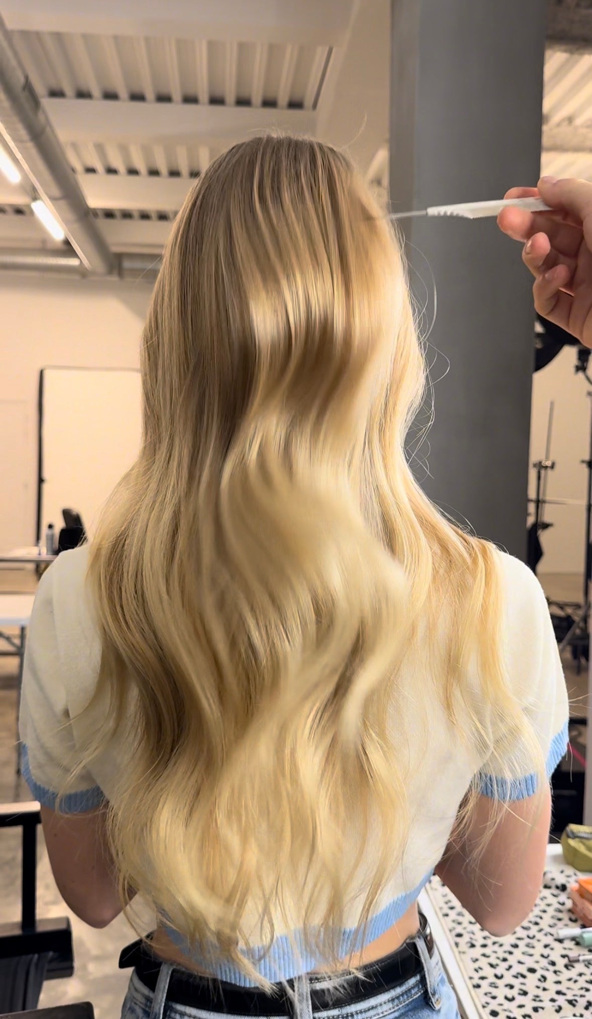 Avant/après en vidéo sur des cheveux blonds : application d’un spray capillaire, puis coiffage. Le résultat révèle des cheveux blonds plus brillants, souples et visiblement lissés.
